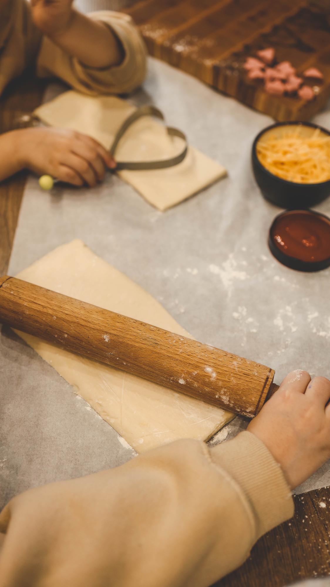 Dettaglio mani che arrotolano un rotolo di pasta fresca